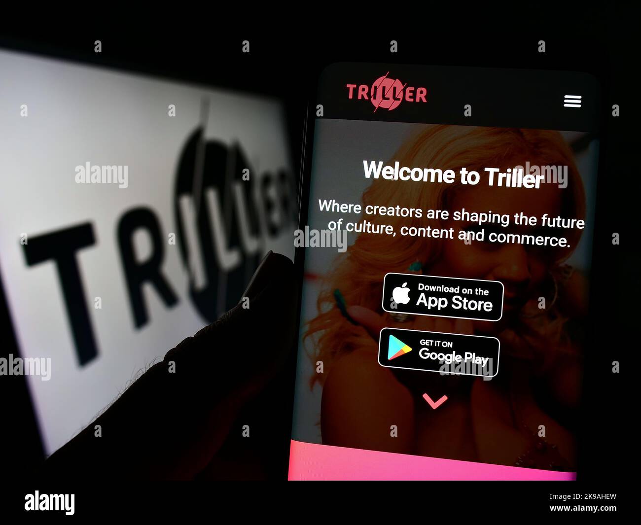 Person holding smartphone with website of US video sharing company Triller Inc. on screen in front of logo. Focus on center of phone display. Stock Photo