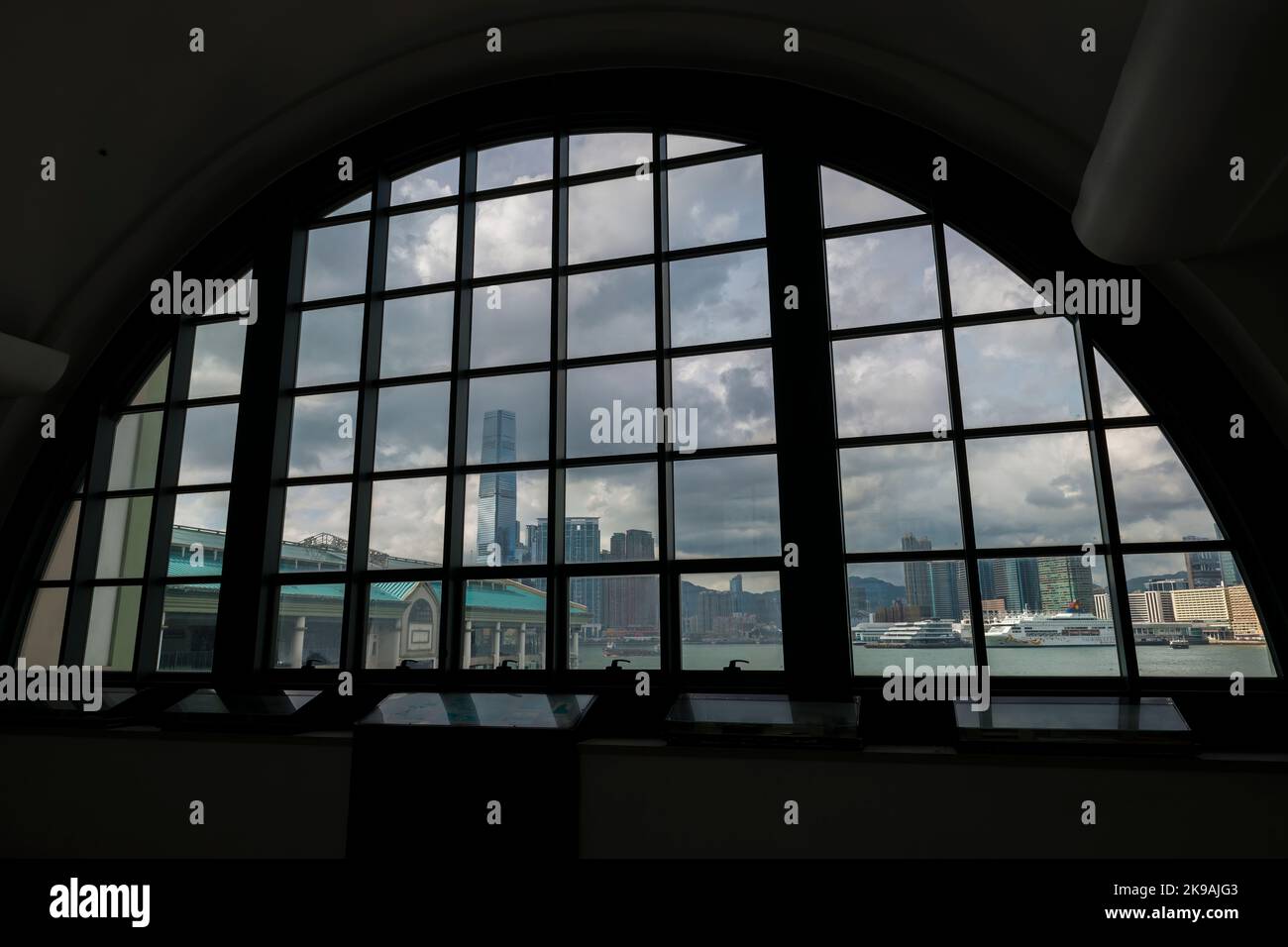 Pier 7, the ICC and Union Square, Ocean Terminal and Harbour City framed by a window of the Central Ferry Pier Link Building, Hong Kong Island Stock Photo