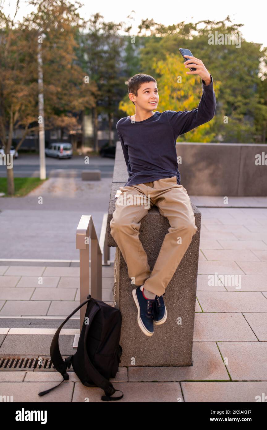 Teen photographing himself with the smartphone camera outdoors Stock Photo