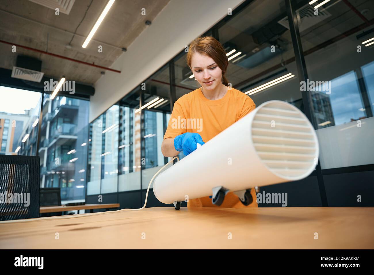Woman installs ozone generator on office desk in coworking area Stock