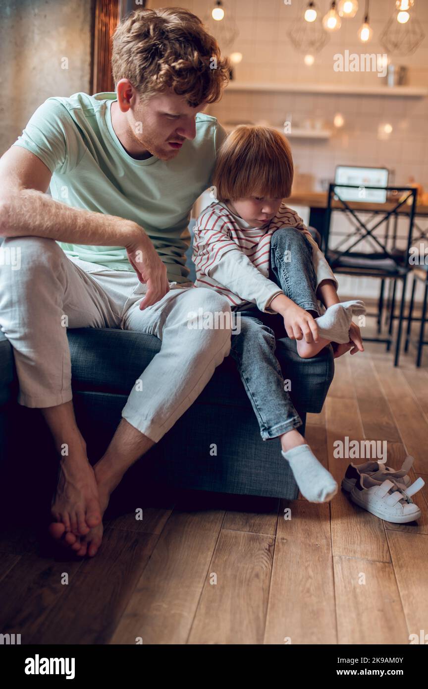 Little boy looking busy while getting on his shoes Stock Photo