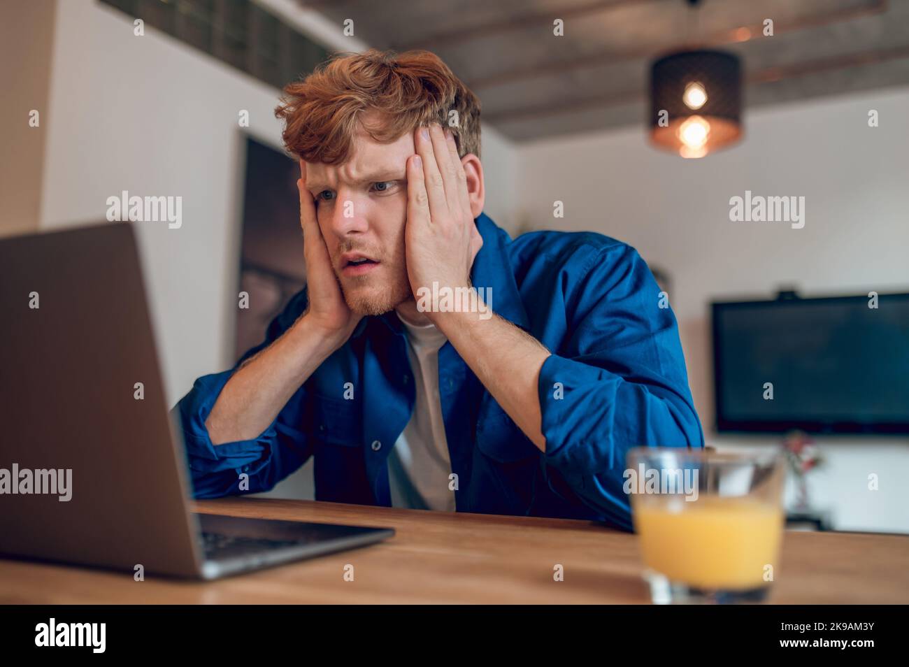 Ginger man reading something onlines and looking shocked Stock Photo