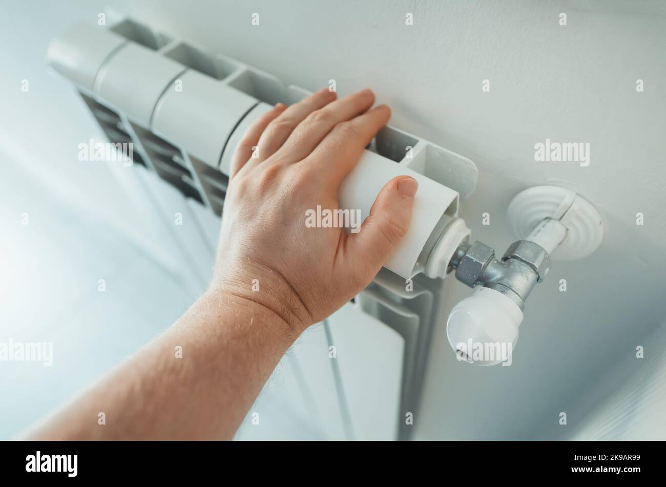 Man's hand checking temperature of heating radiator. Stock Photo