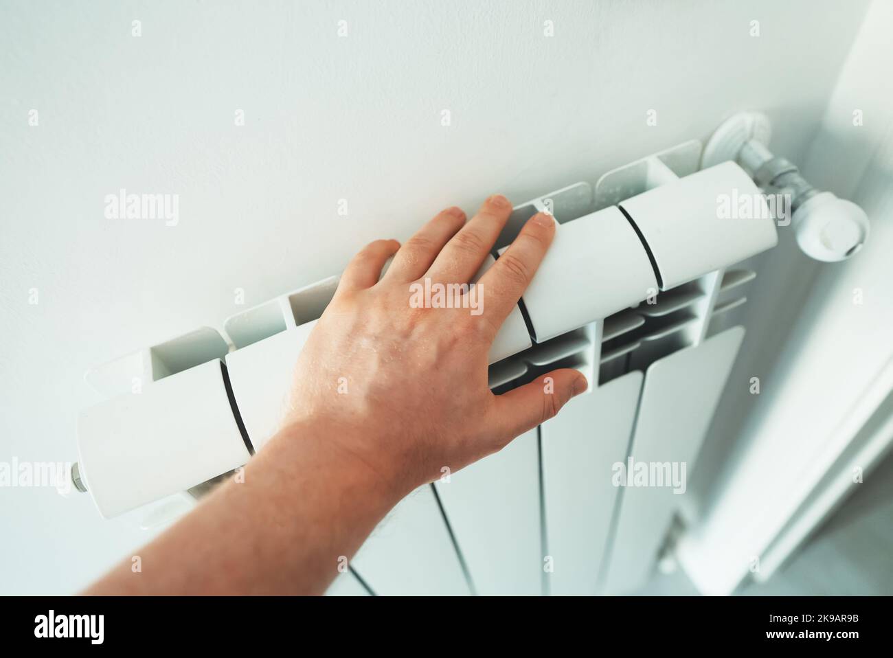 Man's hand checking temperature of heating radiator. Stock Photo