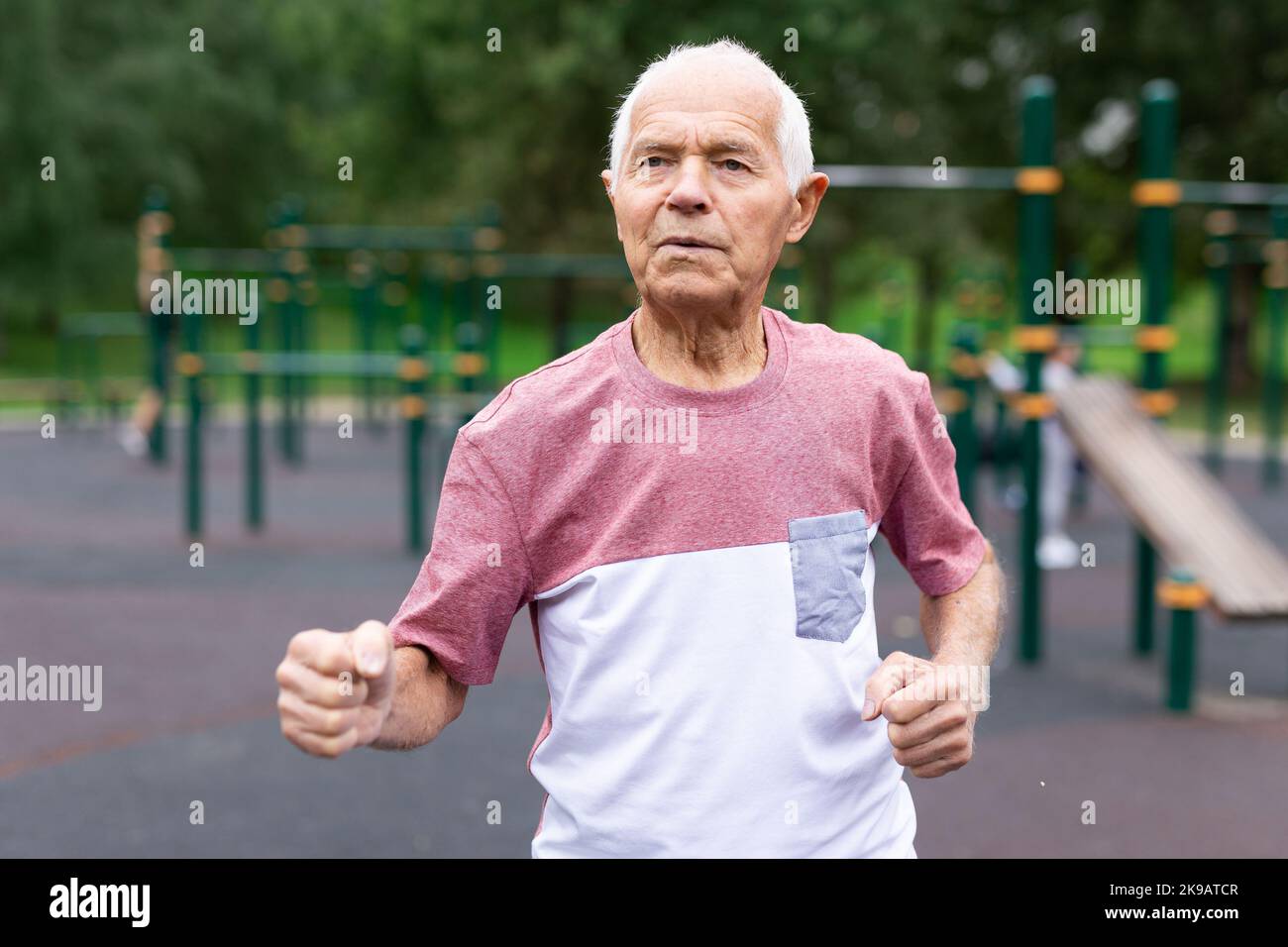Old man running beside playground in urban park Stock Photo - Alamy