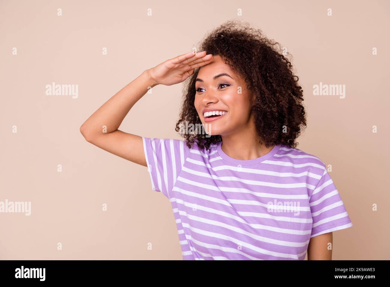 Photo of shiny dreamy girl dressed purple t-shirt arm forehead looking far away empty space isolated beige color background Stock Photo