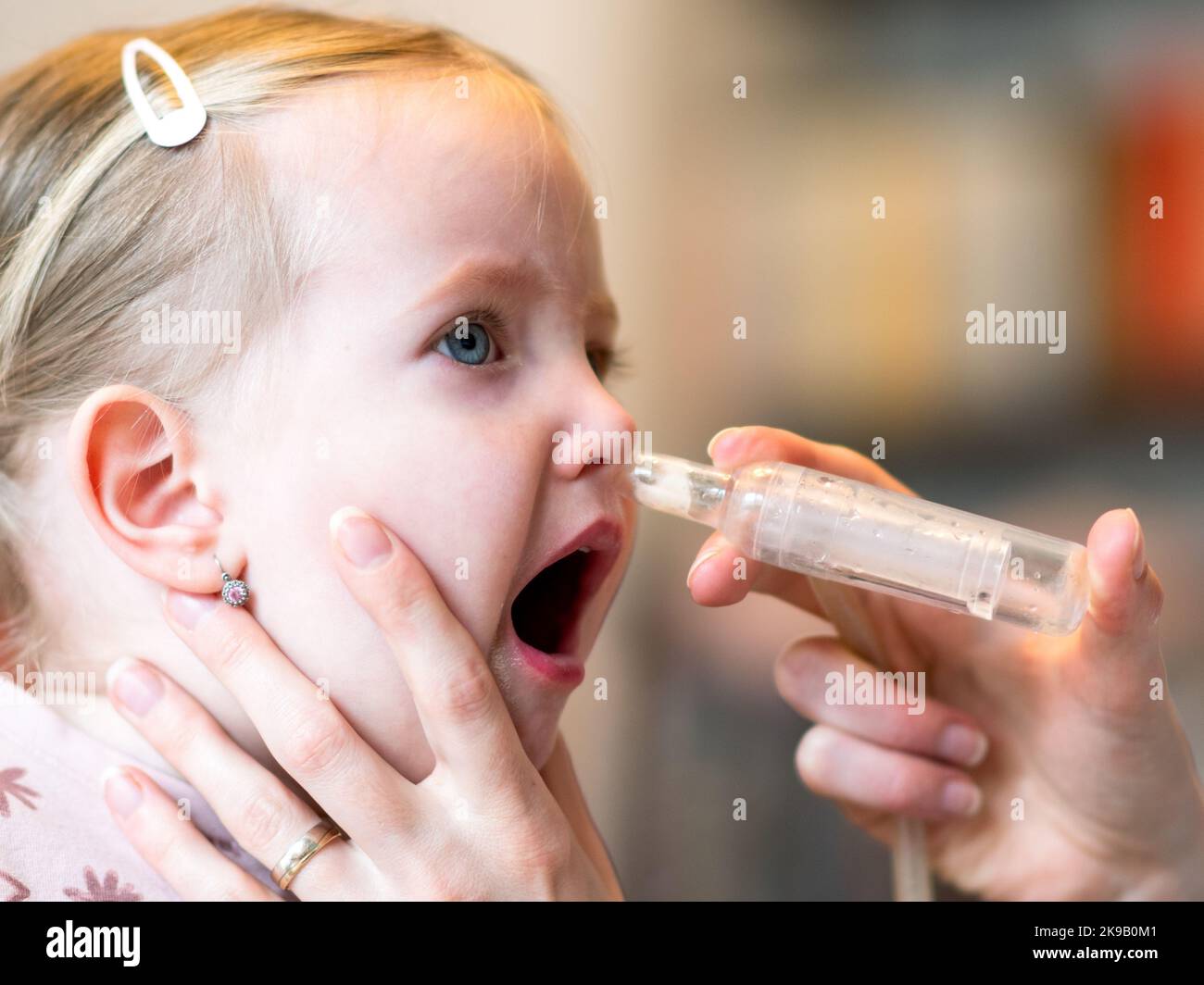 Mother cleaning baby nose. Nasal aspiration connected to vaccum cleaner Stock Photo