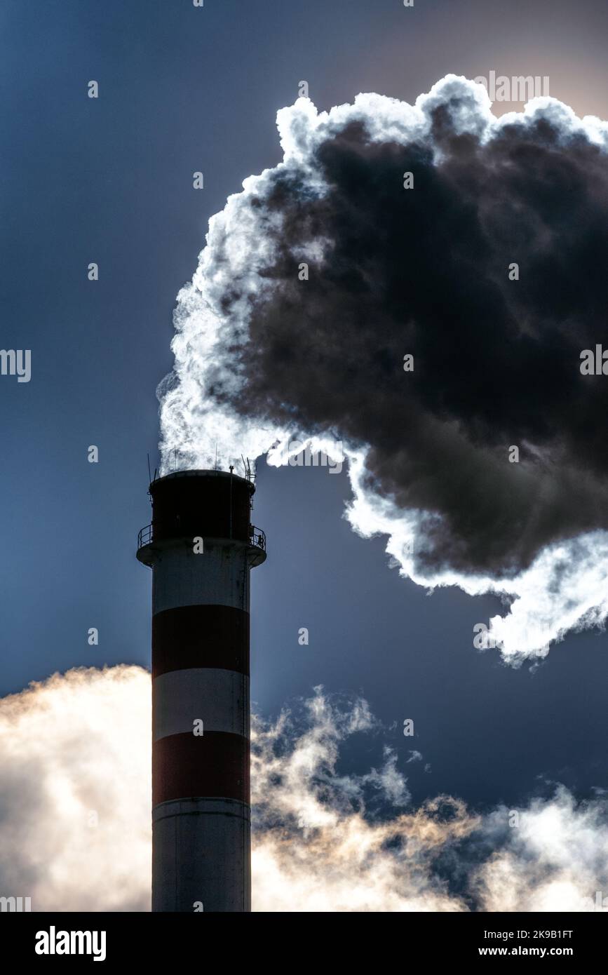 Dark smoke and steam from chimney in factory against the sky Stock Photo