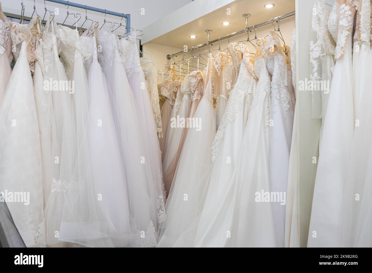 White and cream wedding dresses on a hanger in a bridal boutique. Close up Stock Photo