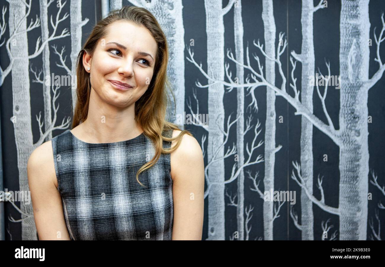 Emotions and Expressions: A Natural Smile. The candidly relaxed and friendly face of a pretty young woman in grey. From a series of related images. Stock Photo