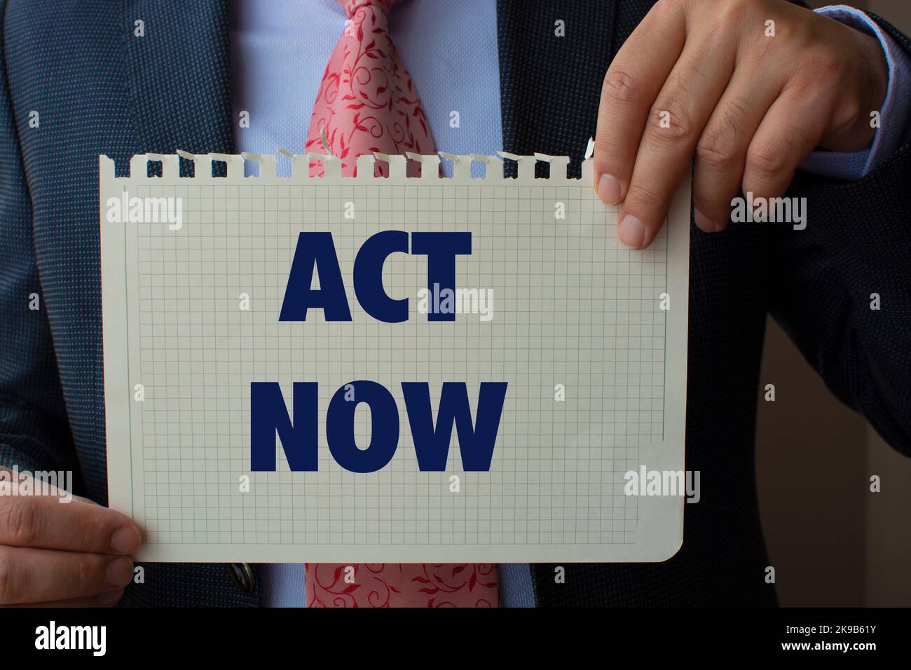 The paper in the suit man's hand read: act now Stock Photo