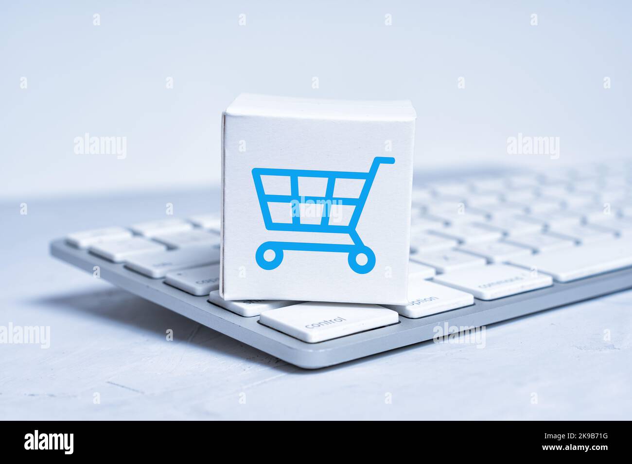 Sealed tiny shipping box with a shopping cart marking placed on a new keyboard. Stock Photo