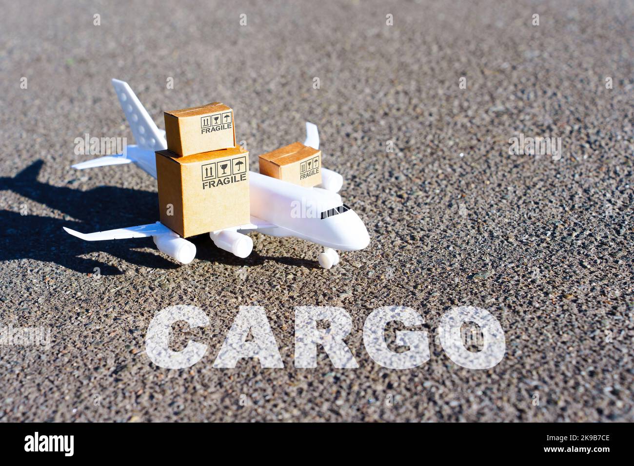Word CARGO written on the runway in front of a toy aircraft carrying