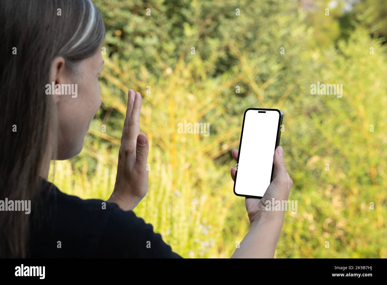 Happy woman wave hand, over shoulder view of Caucasian blonde happy woman wave hand. Video call, online talk concept idea. communication with friend. Stock Photo