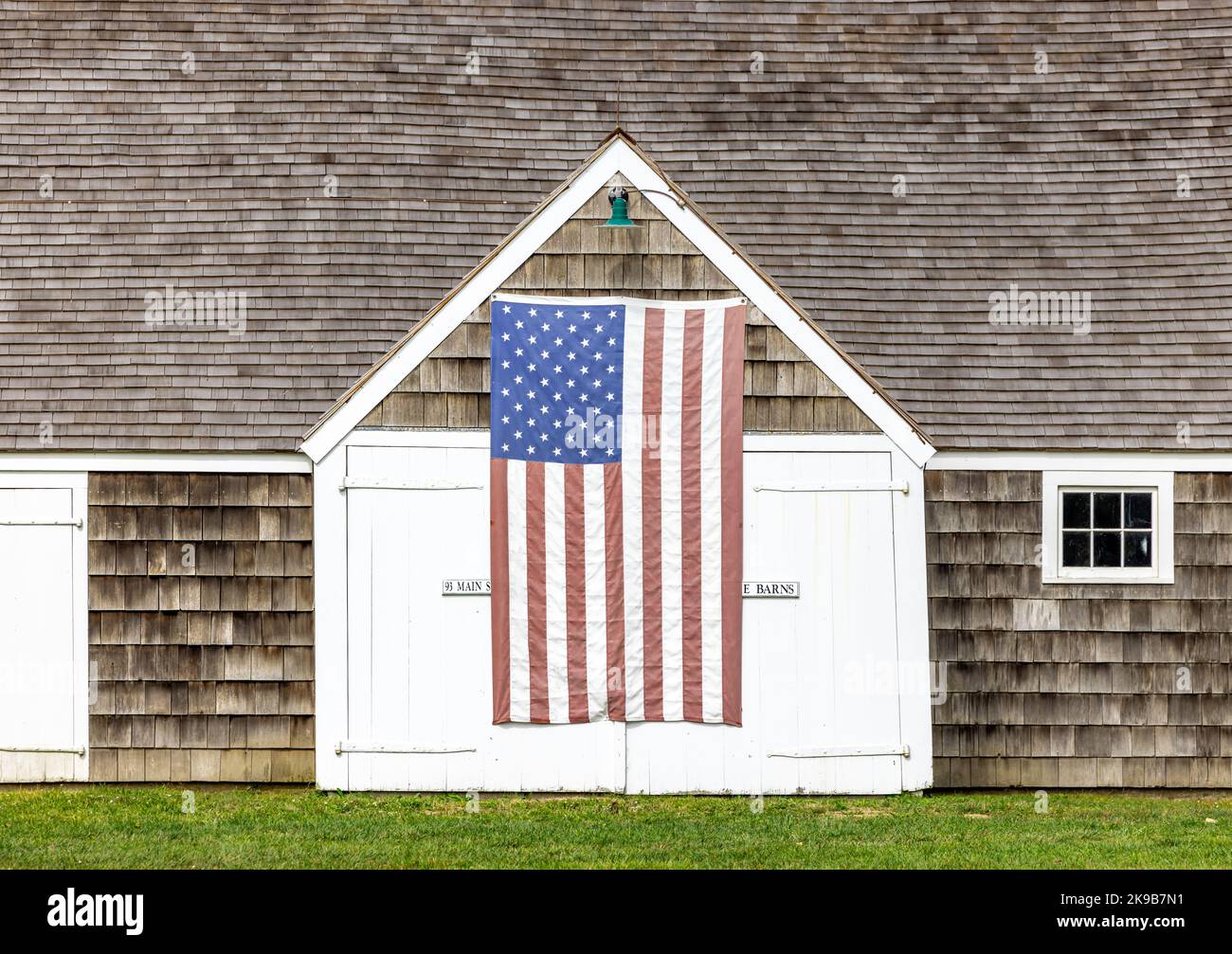 Old Wainscott barn with an American Flag hanging on the front Stock