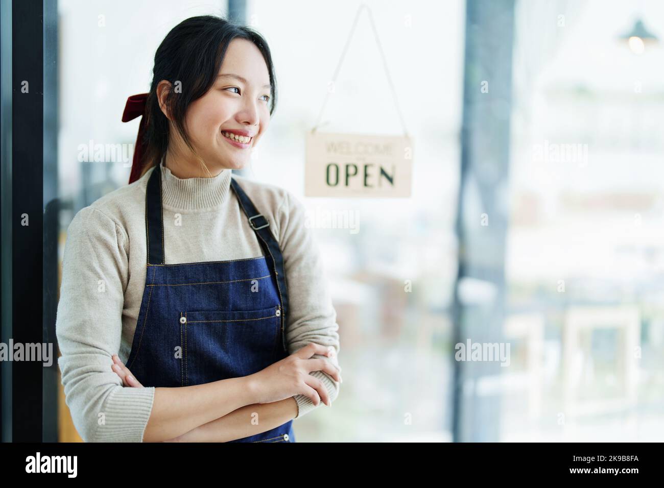 Starting and opening a small business, a young Asian woman showing a smiling face in an apron standing in front of a coffee shop bar counter. Business Stock Photo
