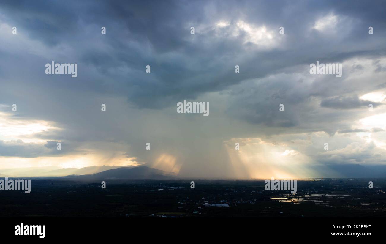 Time lapse of beautiful sky with clouds and sunlight during sunset against the background of silhouettes of mountain landscapes and rural villages. na Stock Photo