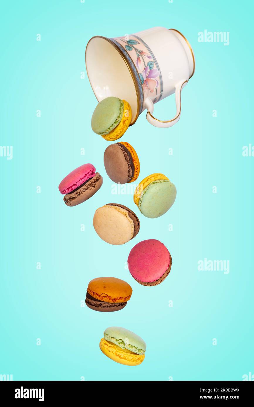 Flying macarons falling from a vintage cup on blue background Stock Photo