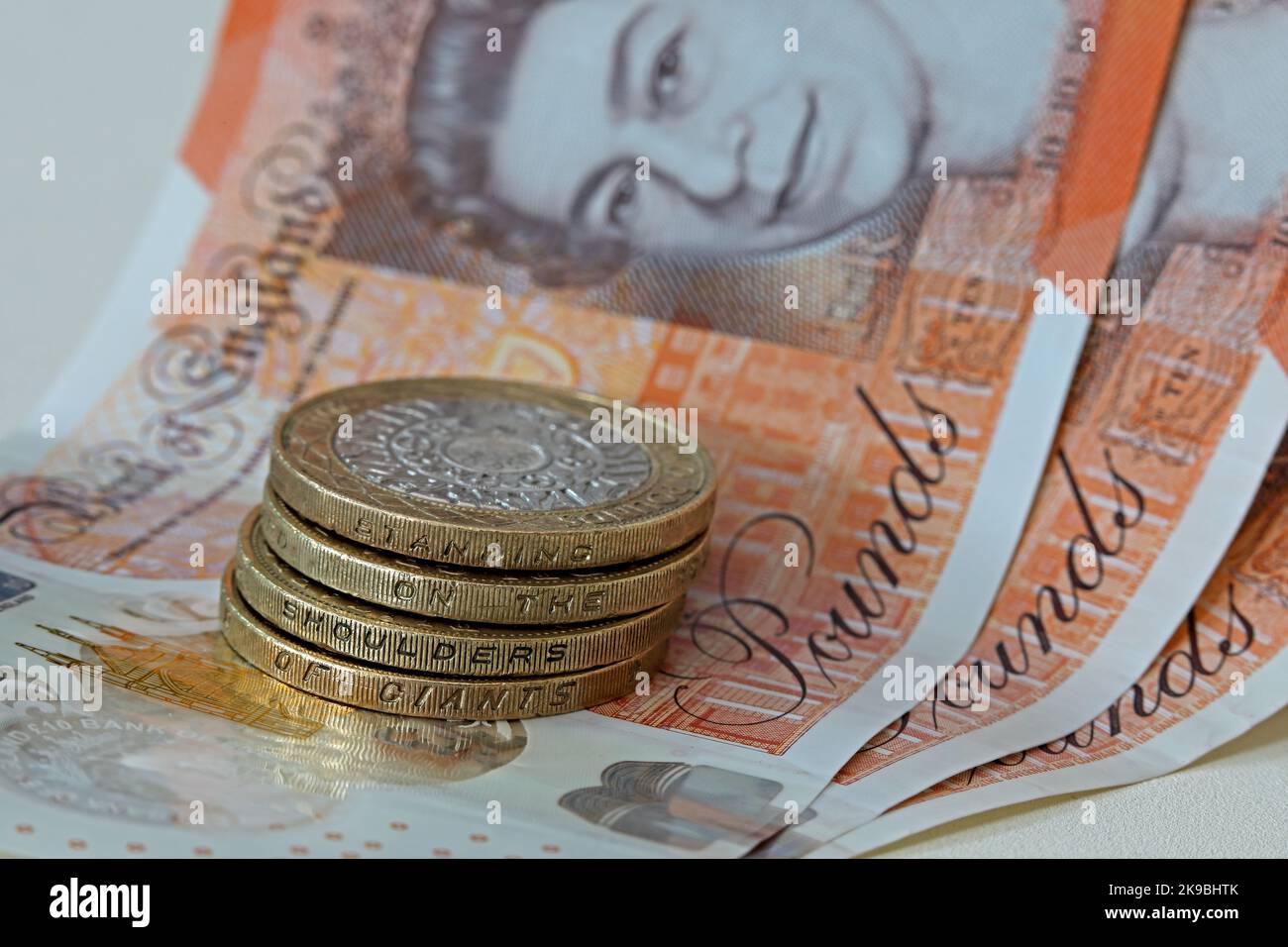 Bank of England, Sterling bank notes, with two pound coins showing inscription, 'Standing on the shoulders of giants'. Coins & note hard currency cash Stock Photo
