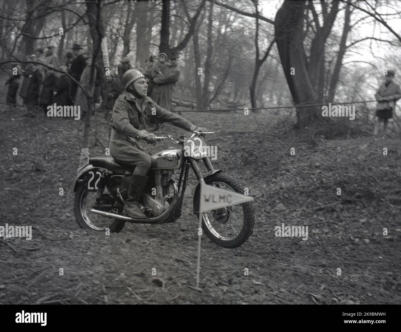 1954, historical, outside on rough terrain in a forest, a male competitor riding a BSA motorcycle taking part in a scramble or trial race at Seacroft, Leeds, England, UK, organised by the West Leeds Motor Club (WLMC), as seen by the letters on the directional arrow. Stock Photo