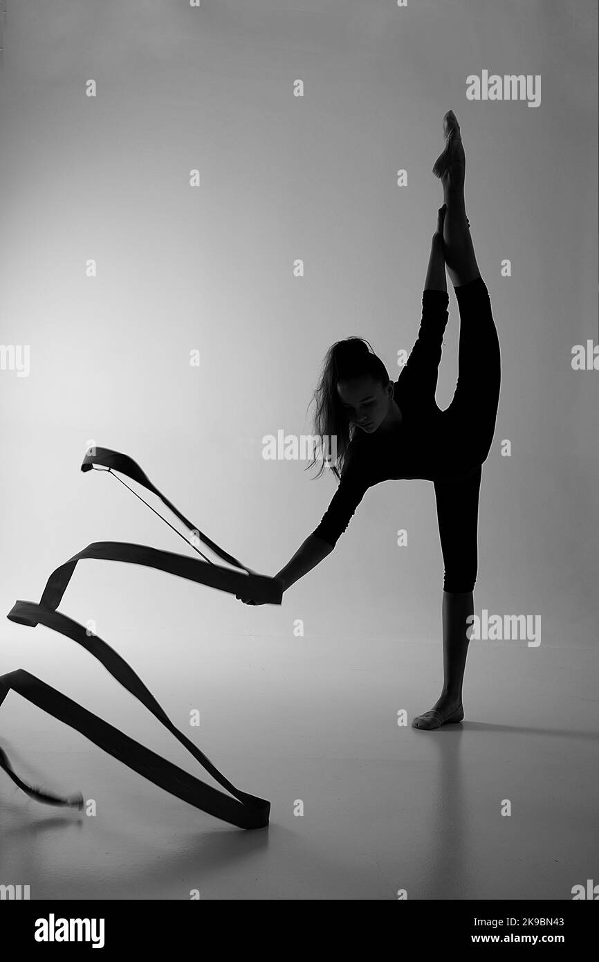 a girl from rhythmic gymnastics in a standing bodysuit shows an