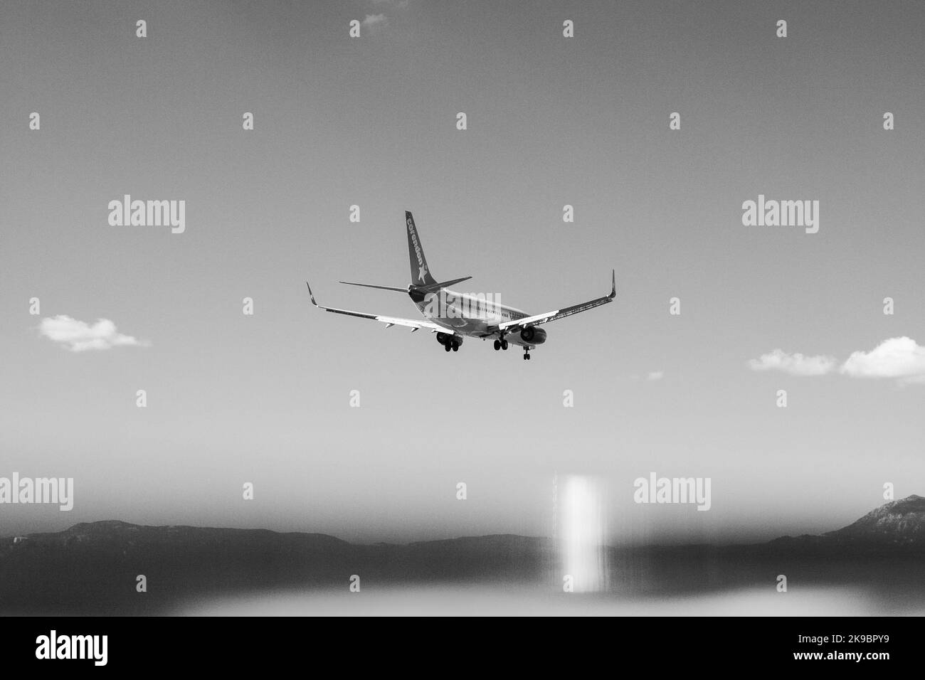 Corfu, Greece 2022.10.04. A passenger plane that flies over water. Huge mountains in the distance. Stock Photo