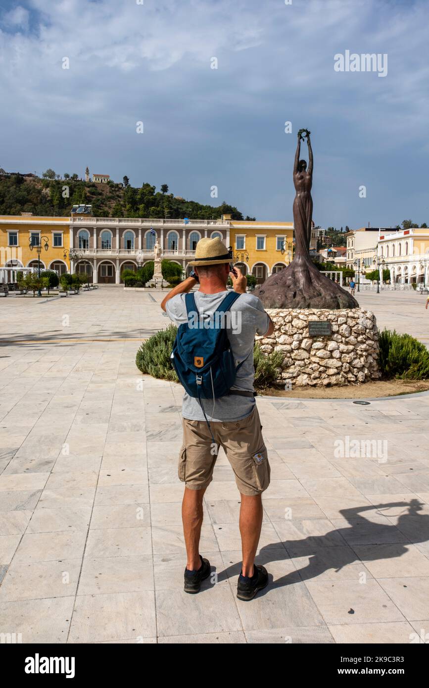 tourist on the greek island of zante or zakynthos photographing a statue in solomos square zante town on a hot summer day. Stock Photo