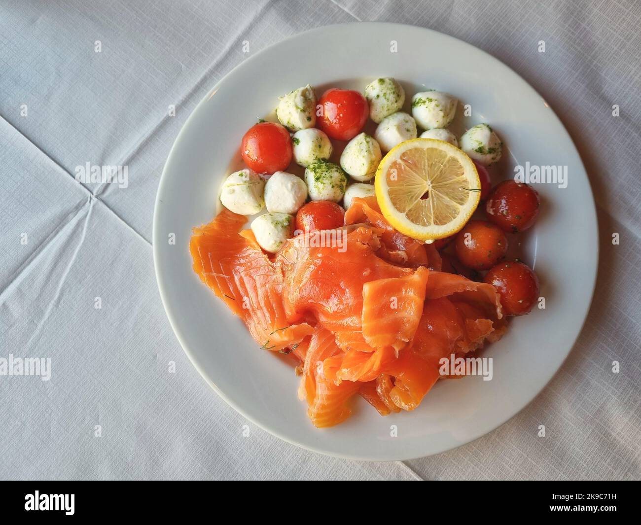 Raw salmon with mozzarella cheese and tomatoes and slice of lemon top view shot Stock Photo
