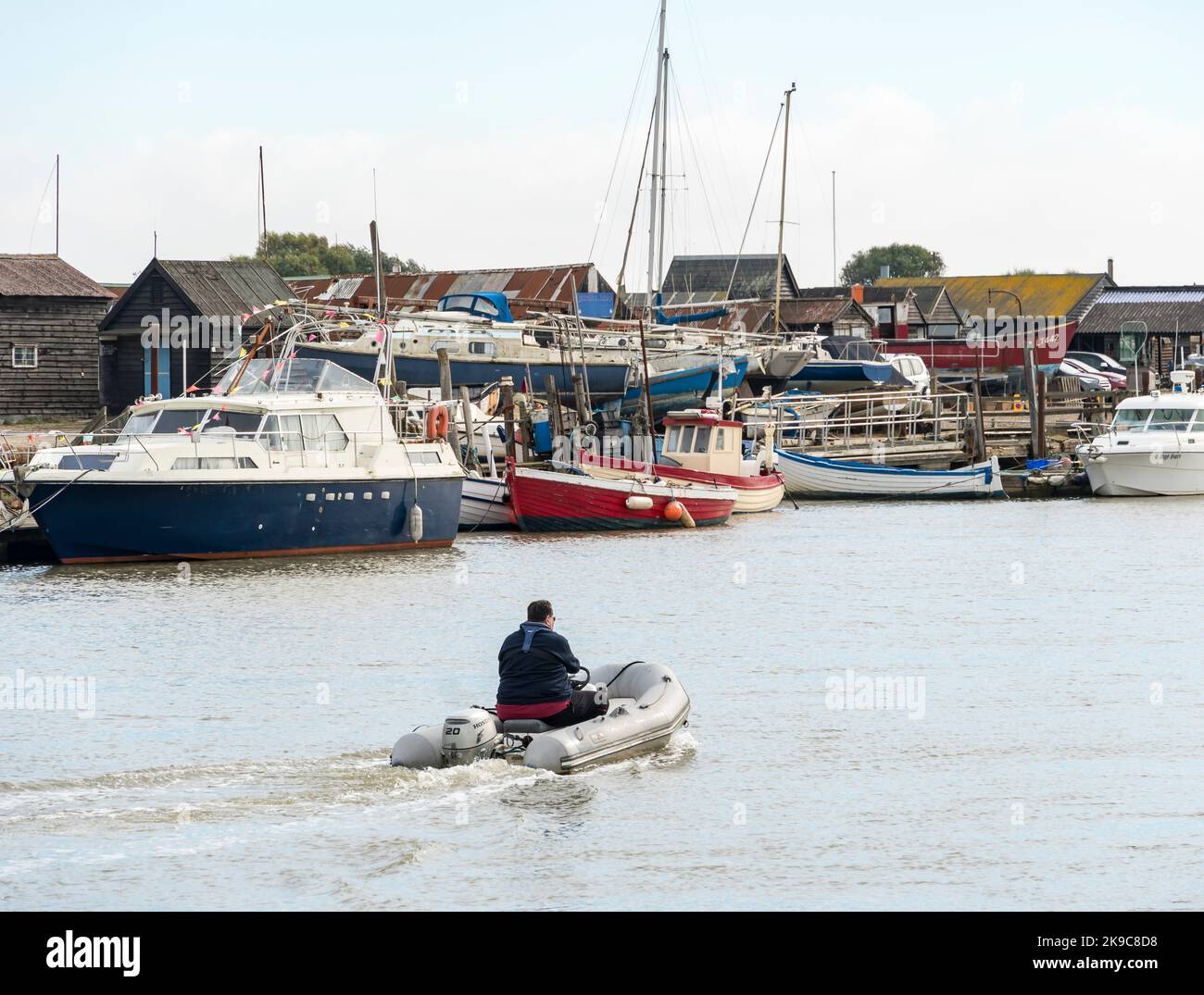 Man piloting inflatable boat down river Blyth southwold harbour 2022 Stock Photo