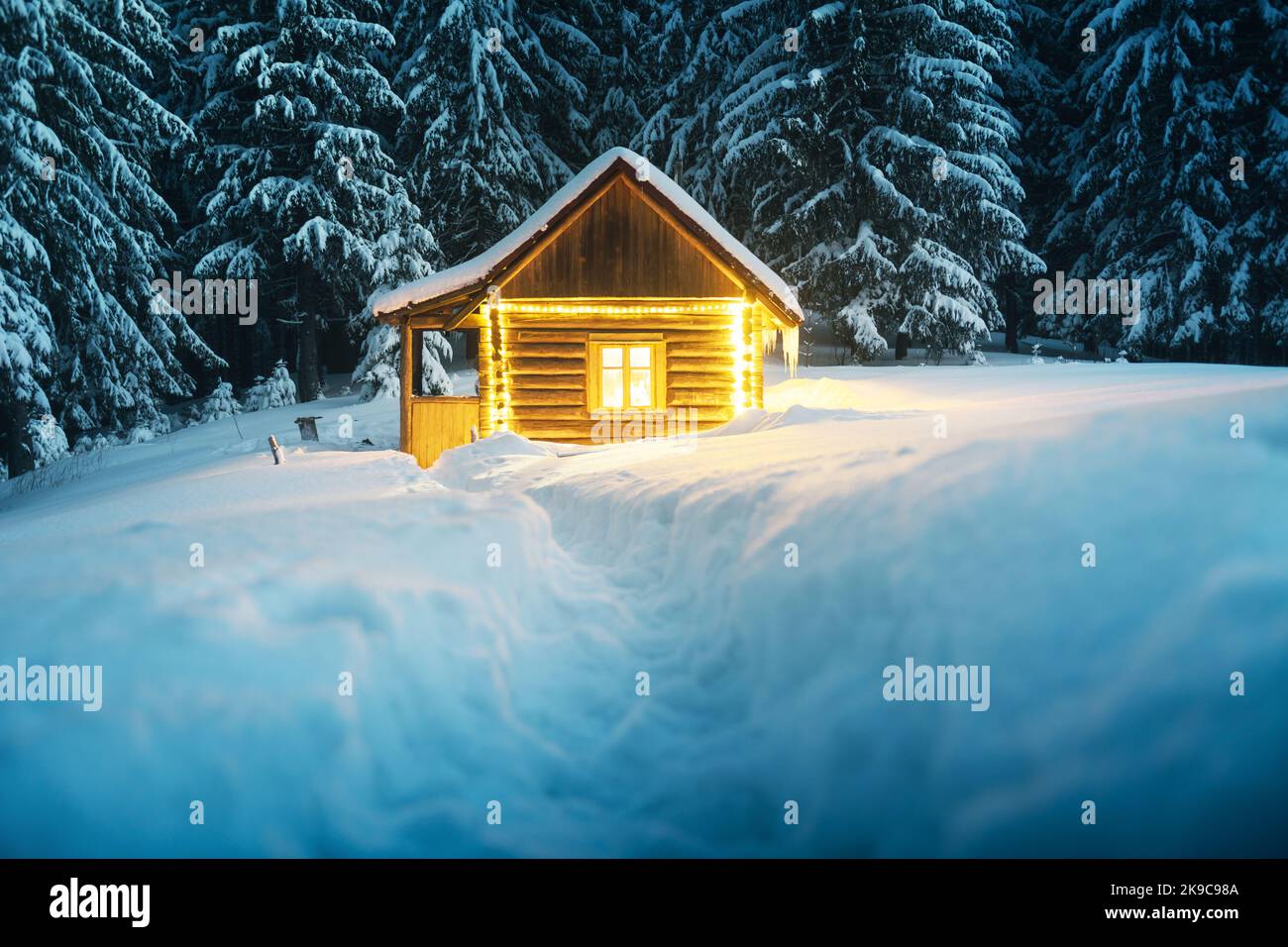Fantastic winter landscape with glowing wooden cabin in snowy forest ...