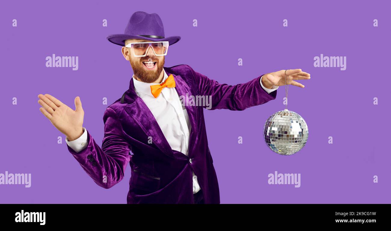 Cheerful extravagant man with shiny mirror disco ball having fun on purple background. Stock Photo