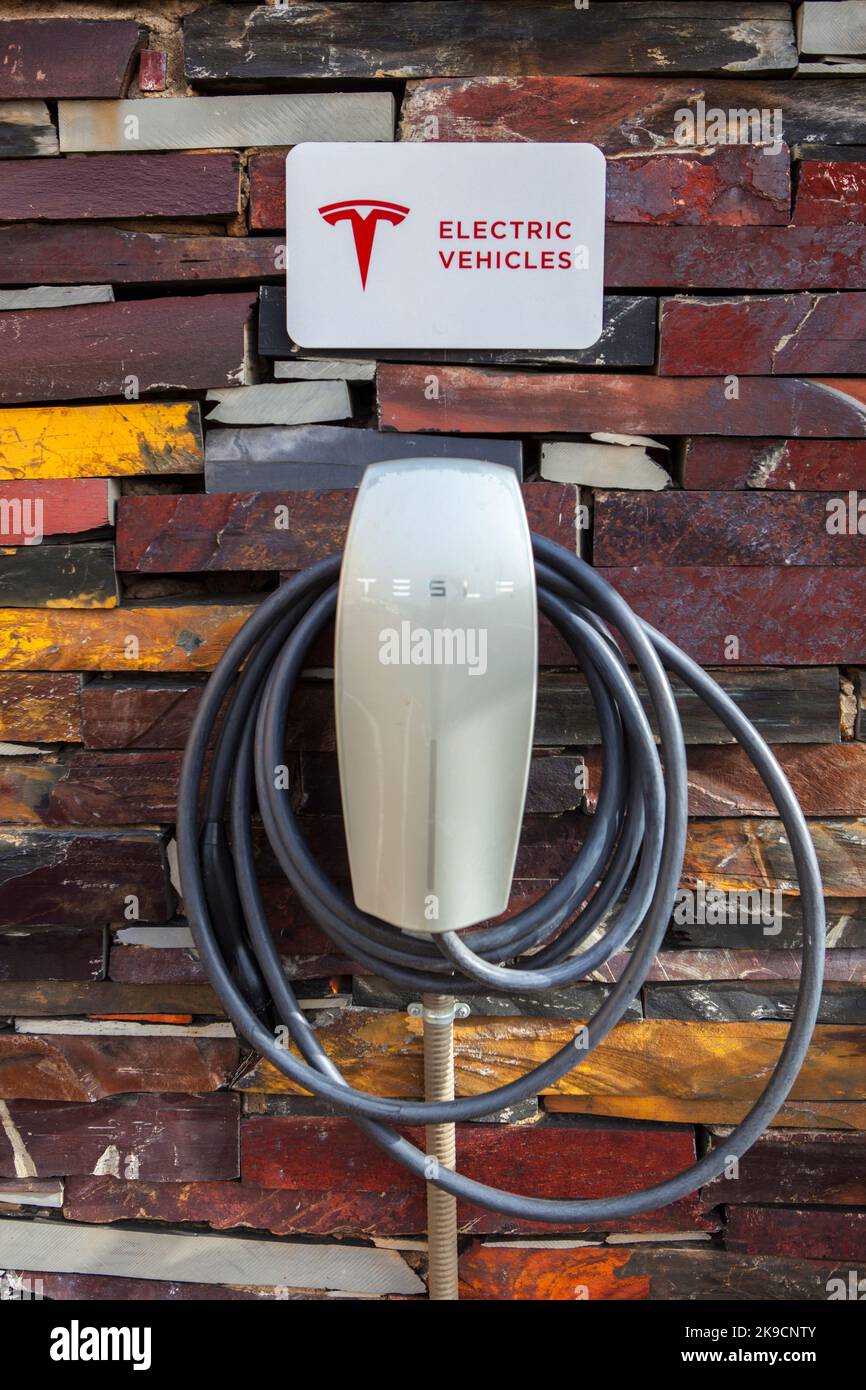Alcantara, Spain - Oct 6th, 2022: Tesla Electric car charging station at rural enviroment. Natural rust slate wall. Alcantara Caceres, Spain. Stock Photo
