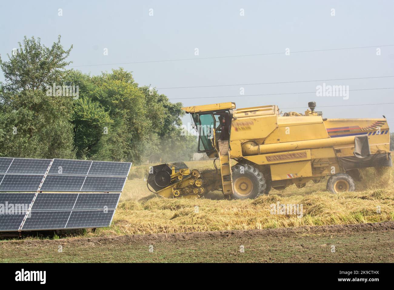 Solar powered irrigation system and combine harvester in the field Stock Photo