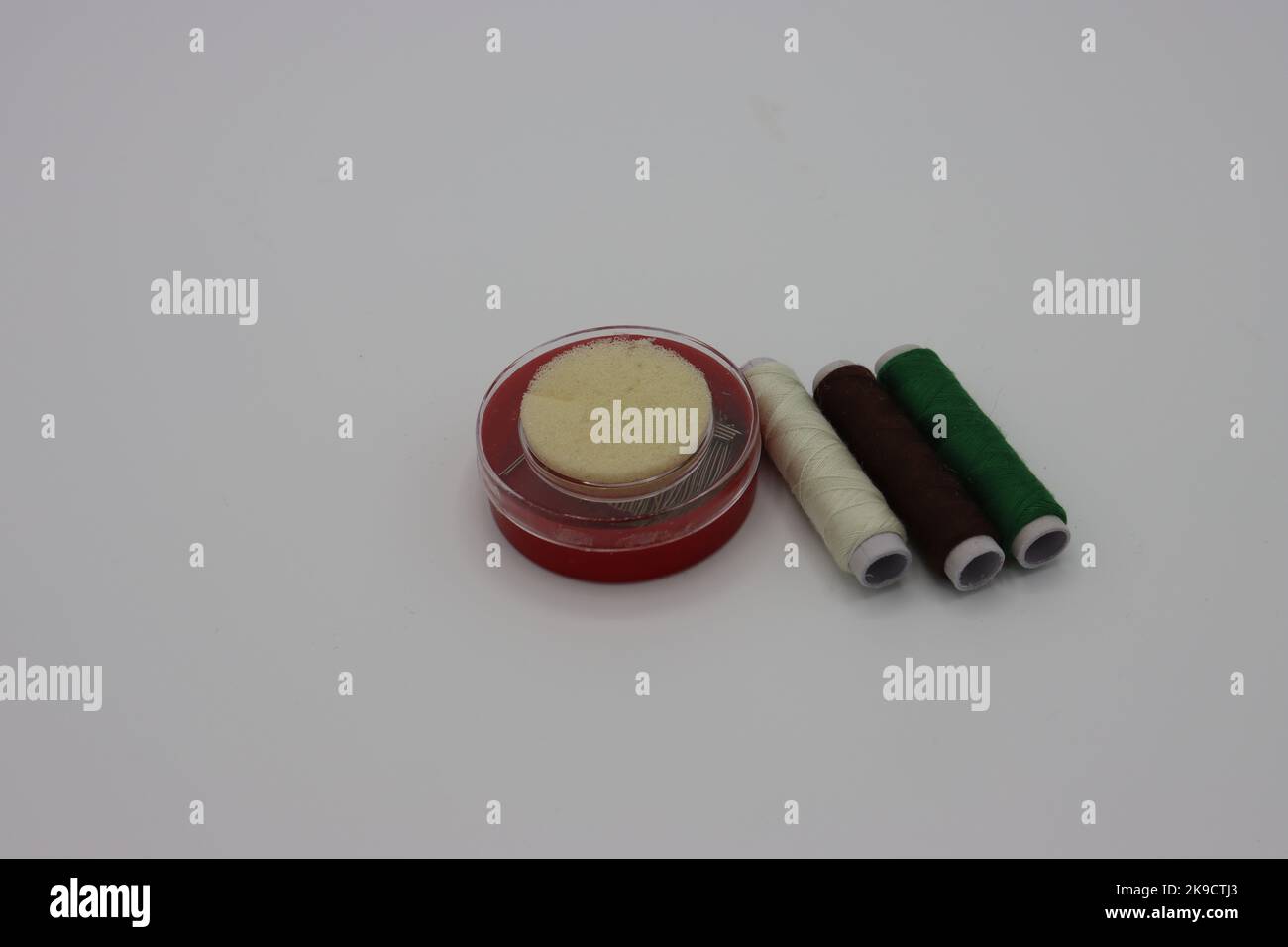 Sewing accessories on a white background. Pins in a circular plastic box, threads Stock Photo