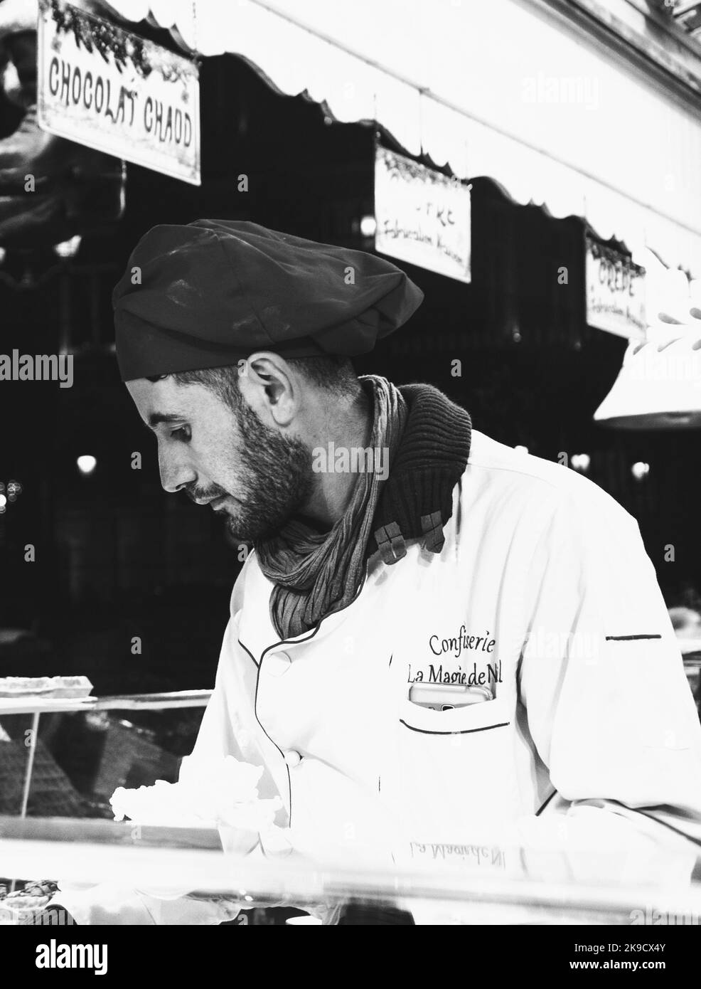 PARIS, FRANCE - JANUARY 6, 2019:  Vendor in red Santa chef hat prepares and sales traditional fresh waffles and crepes at Christmas market during wint Stock Photo