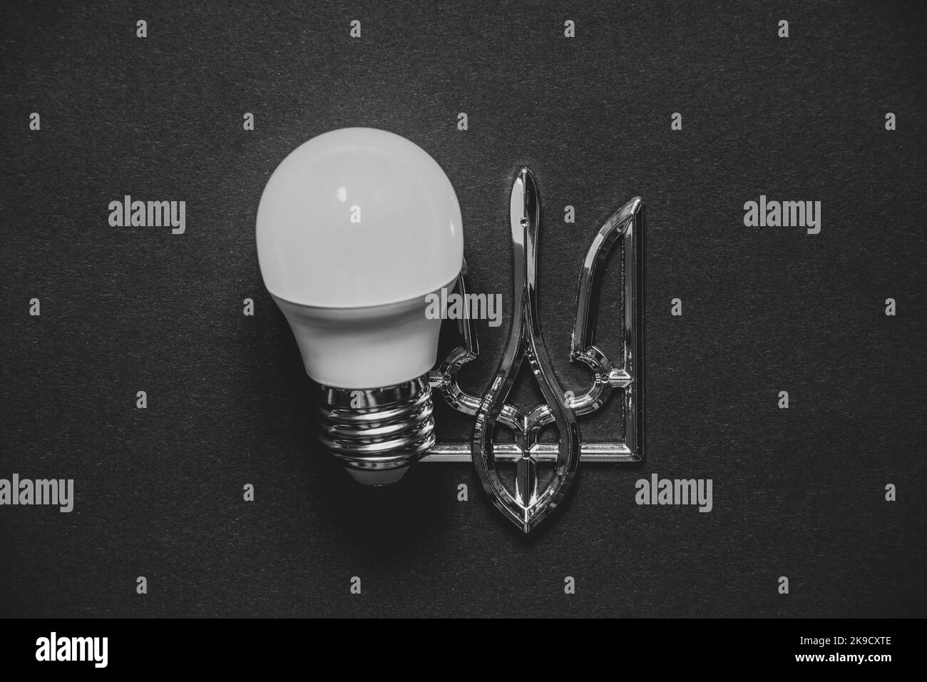 LED lamp and coat of arms of Ukraine on a black background, Ukraine without light, energy crisis, war Stock Photo