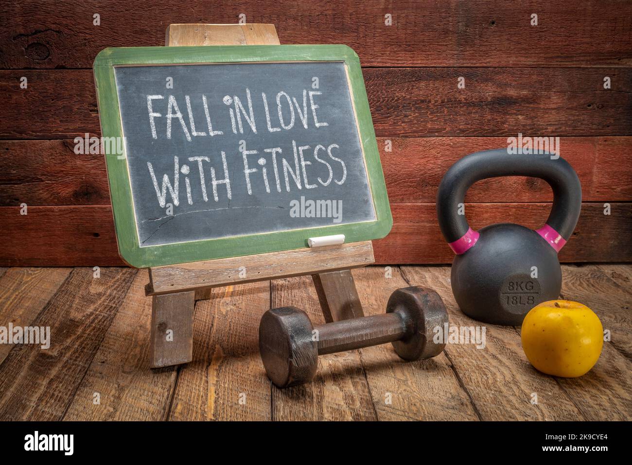 fall in love with fitness - white chalk handwriting on a slate blackboard with kettlebell and dumbbell, inspirational fitness concept Stock Photo