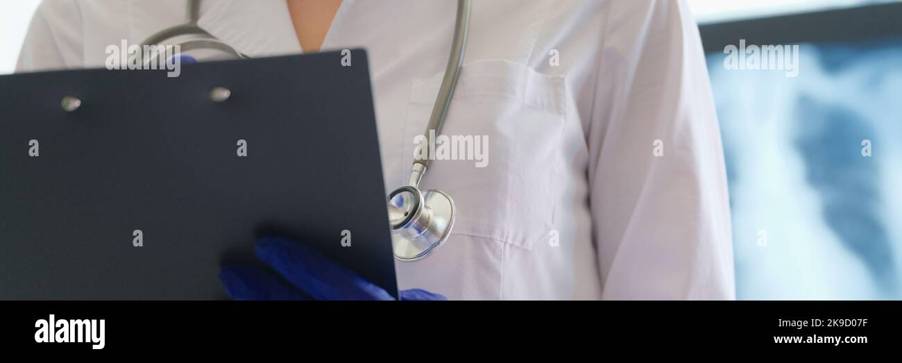 Radiologist checks xray image and holds clipboard in hands Stock Photo