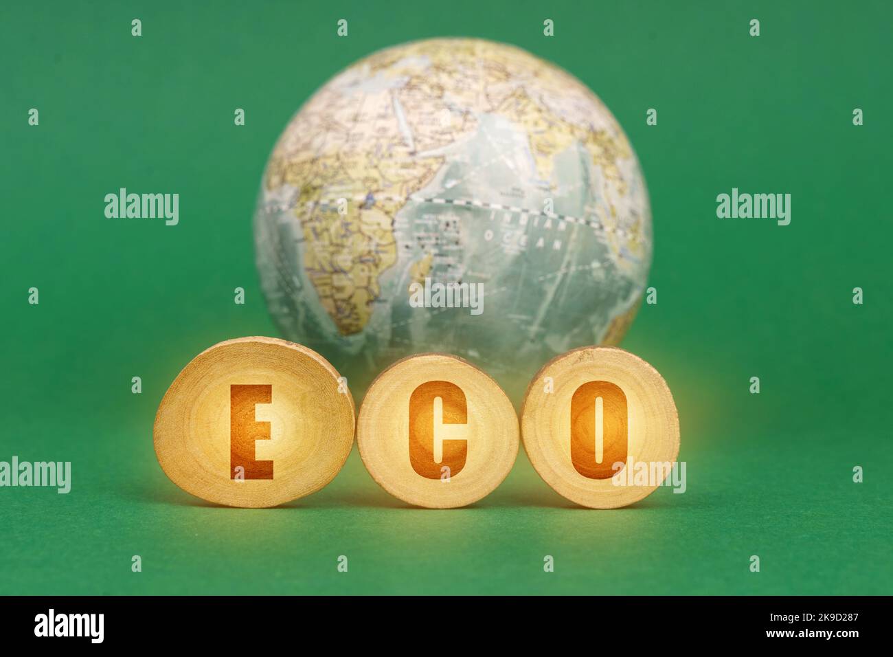 Ecological concept. On a green background, a globe and wooden circles with the inscription - ECO Stock Photo