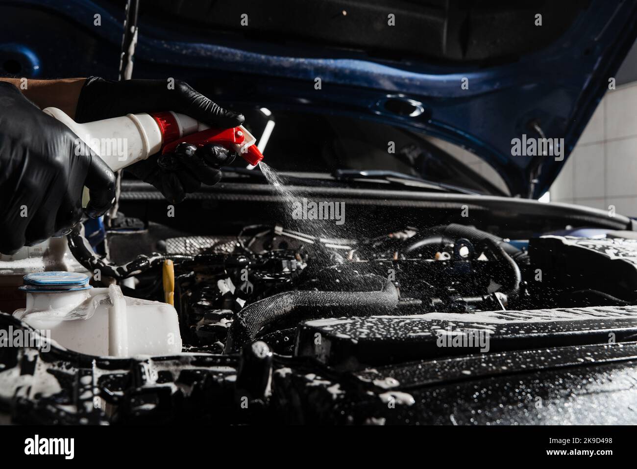 Washing car engine with spray and detergent in detailing auto service
