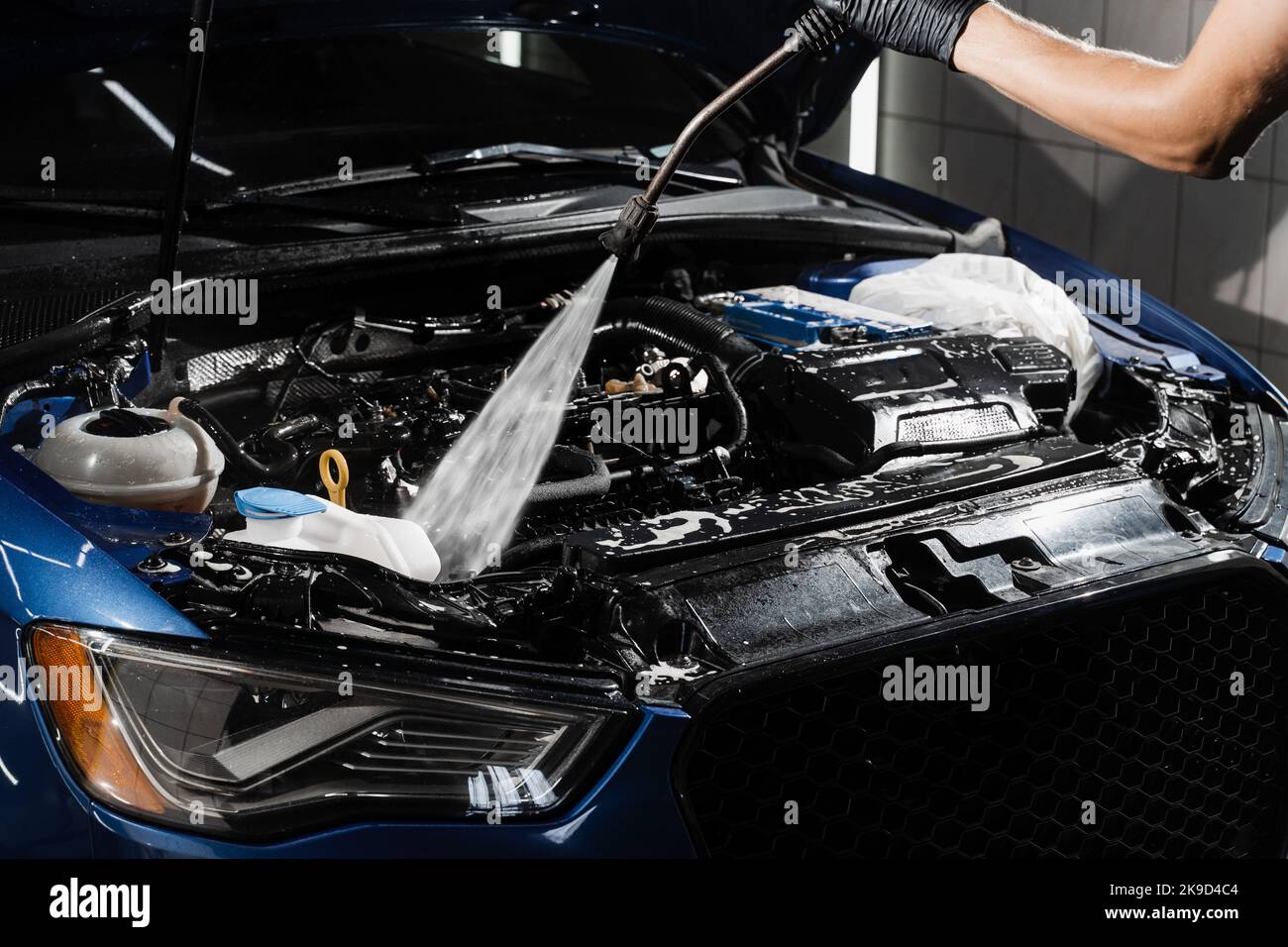 Detailing cleaning motor from dust and dirt. Pouring water on car