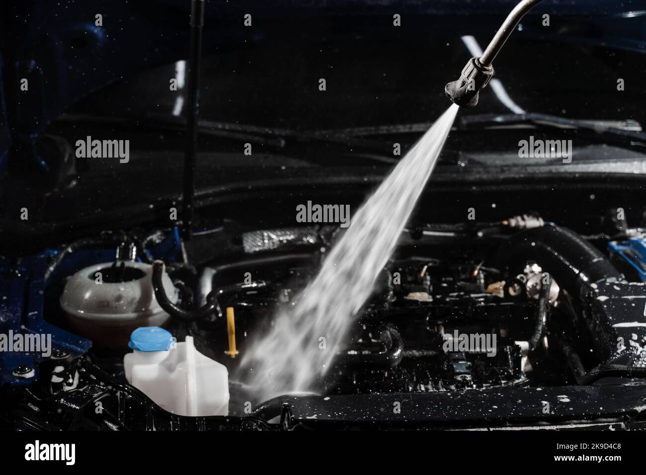 Detailing cleaning motor from dust and dirt. Pouring water on car