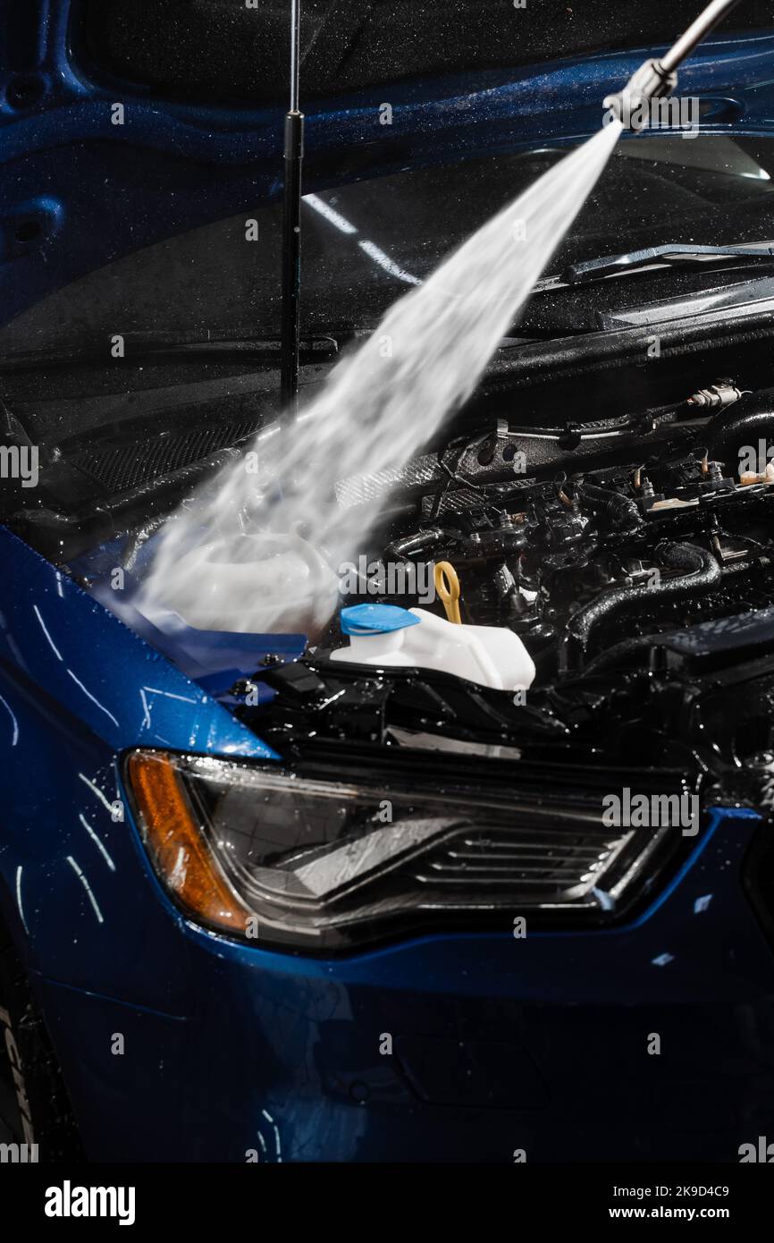 Detailing cleaning motor from dust and dirt. Pouring water on car