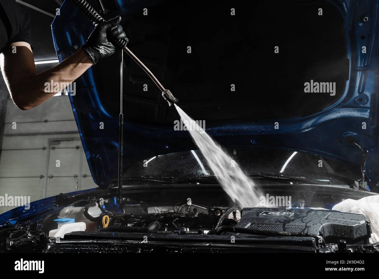 Washing car engine with with water in detailing auto service. Detailing cleaning motor from dust