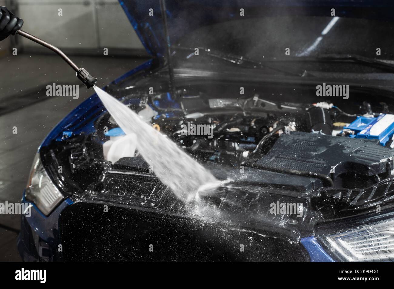 Washing car engine with with water in detailing auto service. Detailing cleaning motor from dust