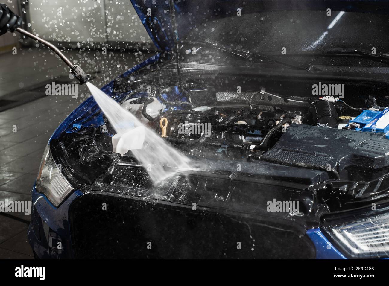 Washing car engine with with water in detailing auto service. Detailing cleaning motor from dust