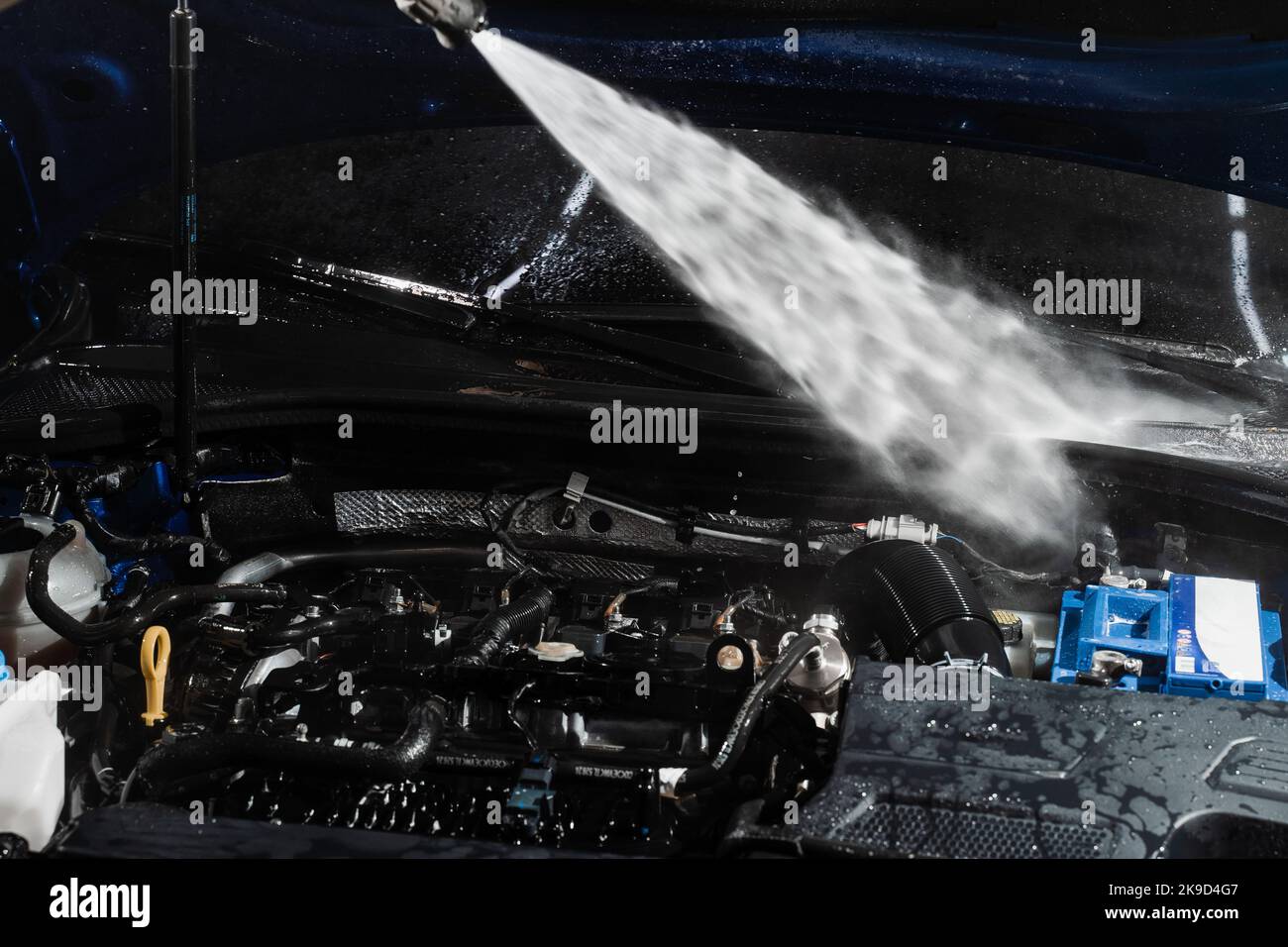 Washing car engine with with water in detailing auto service. Detailing cleaning motor from dust