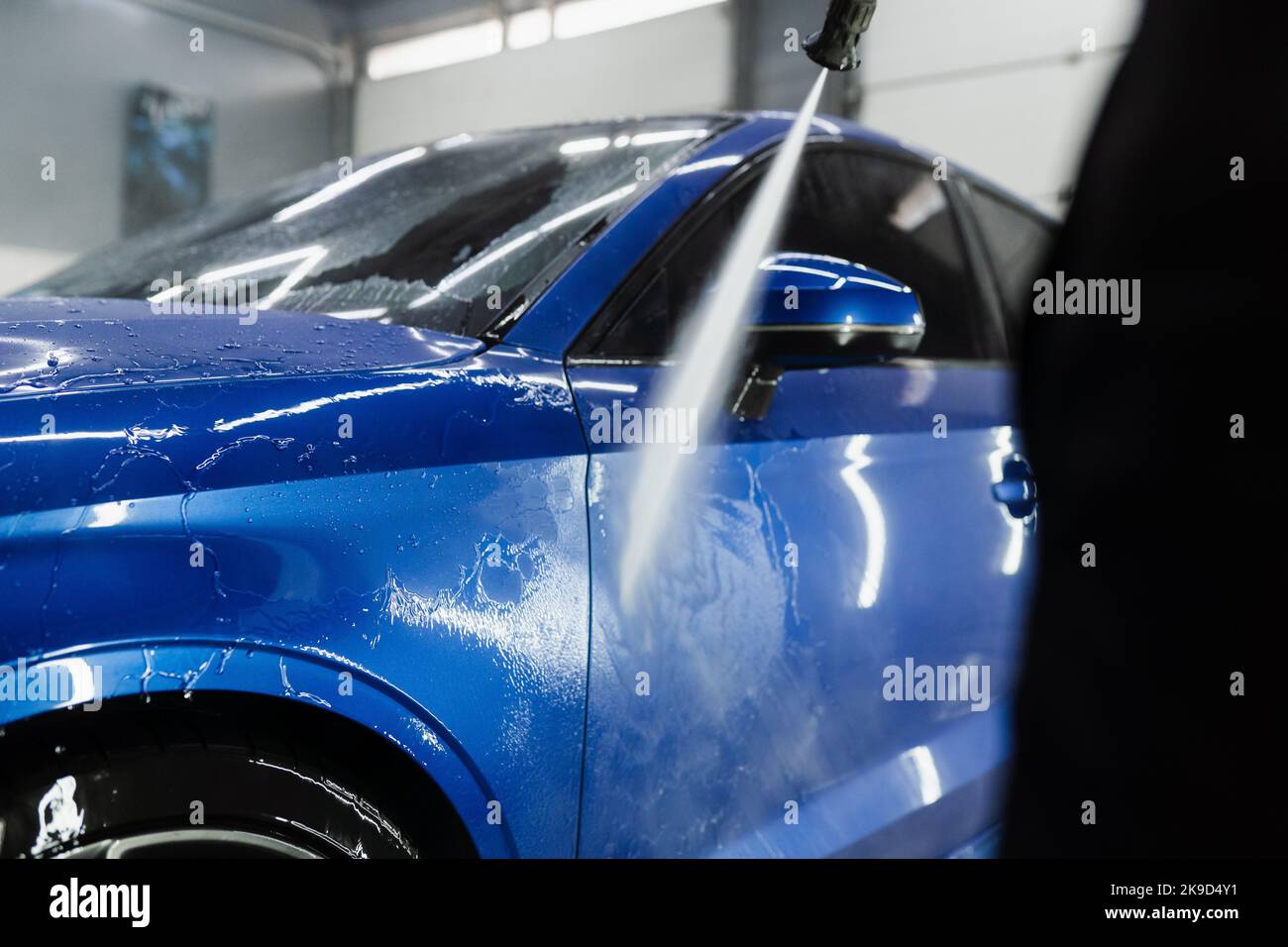Car washer pouring water for full body car wash. Spraying water on car
