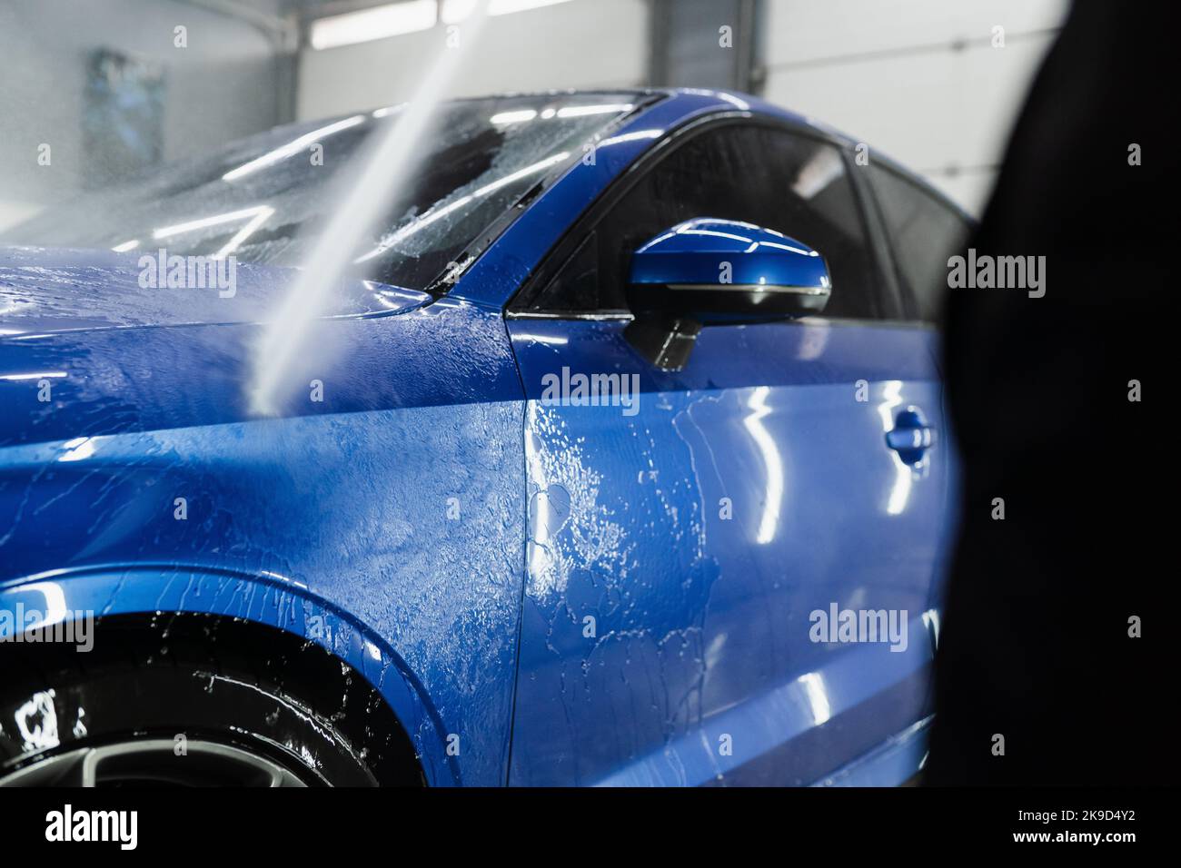 Car washer pouring water for full body car wash. Spraying water on car