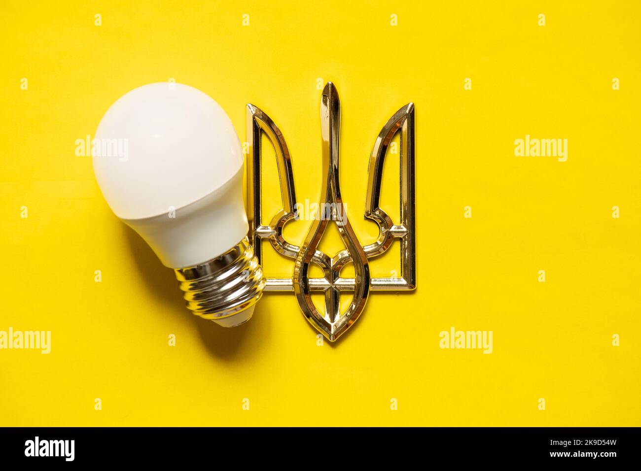 LED lamp and coat of arms of Ukraine on a yellow background, Ukraine without light, energy crisis, war 2022 Stock Photo